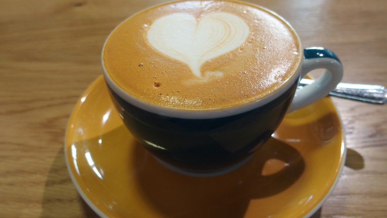 Cappuccino mit Herz-Latte-Art in blauer Tasse auf Holztisch., © Donau Niederösterreich