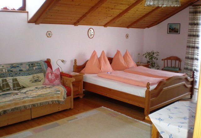 Gemütliches Schlafzimmer mit Holzbett, Sofa und Dachschräge., © Sundl