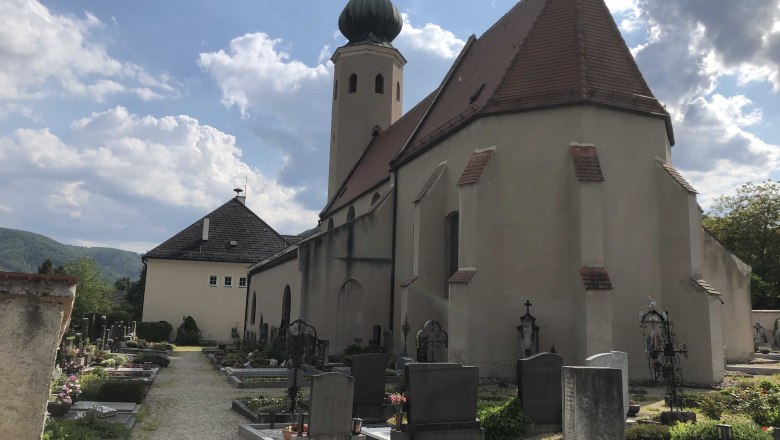 Kirche mit Friedhof, umgeben von Hügeln und bewölktem Himmel., © Donau NÖ Tourismus